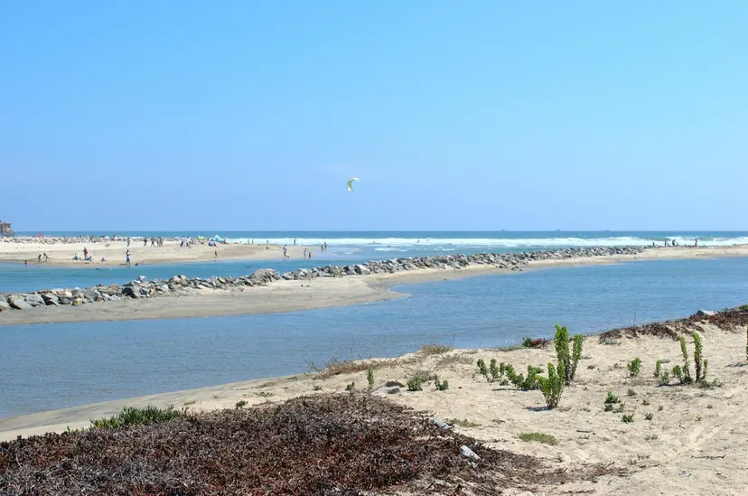 The Santa Ana River mouth: river water and a rock jetty in the middle distance, with the beach and breaking waves beyond